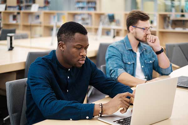 Adult student in library using laptop