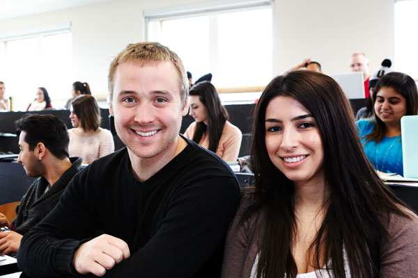 Two students in lecture hall smiling